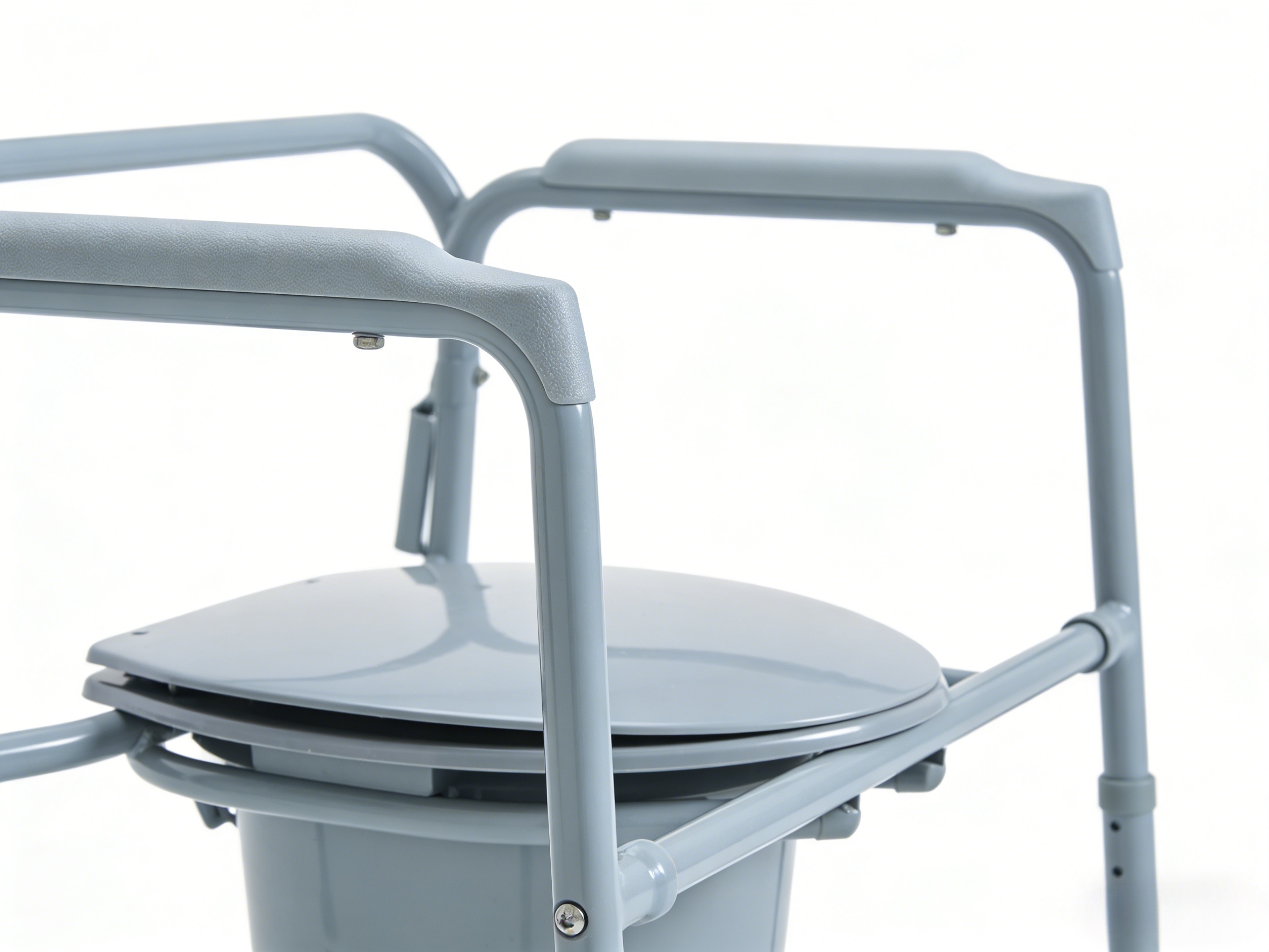 Primer plano de soldadura de precisi&oacute;n y apoyabrazos acolchados de alta densidad en una silla con inodoro bari&aacute;trico plegable de calidad profesional.